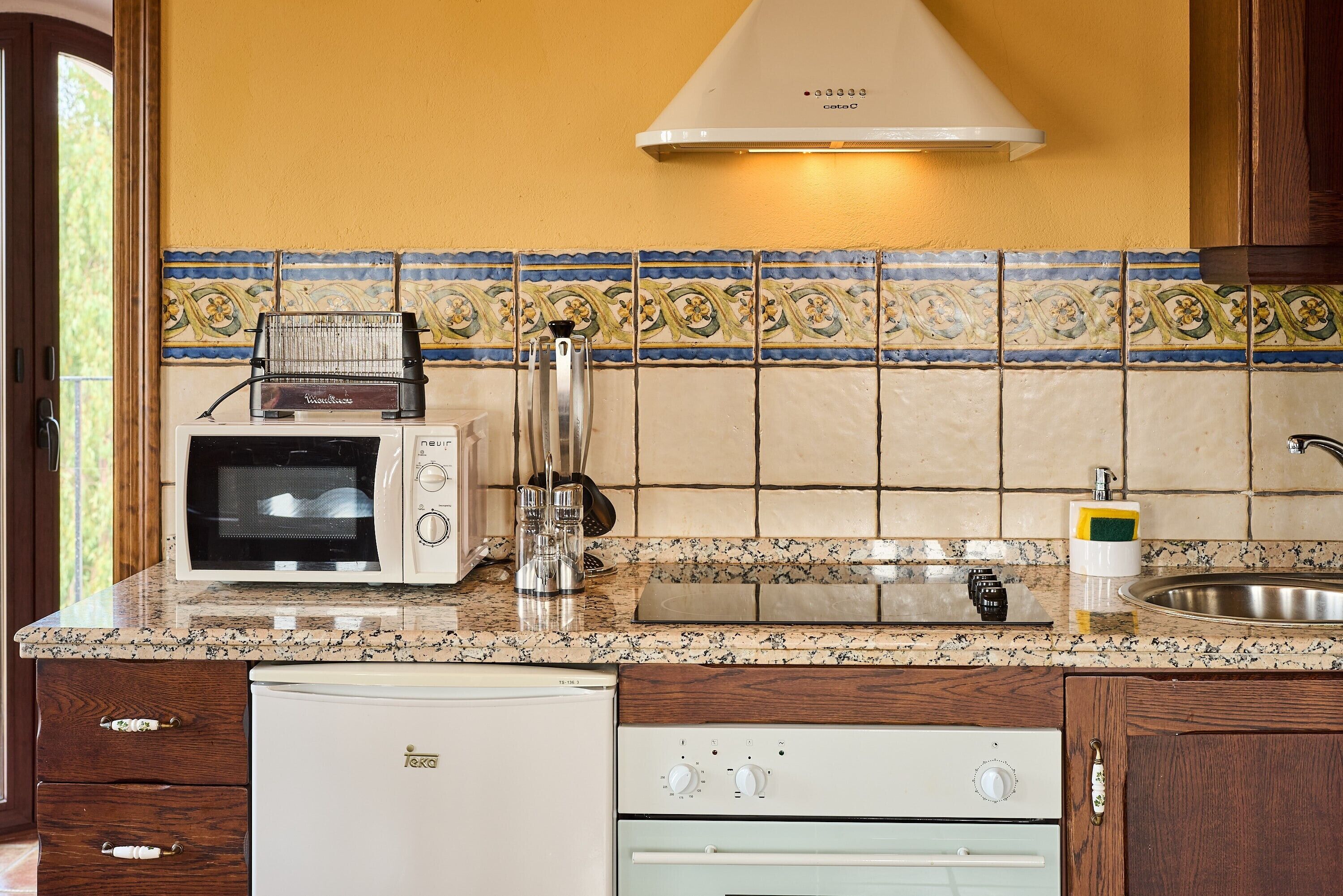 Una cocina con microondas, tostadora, lavabo y escurreplatos.