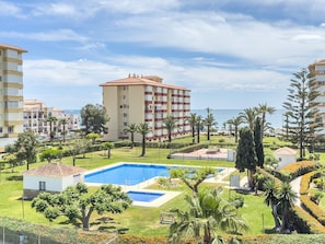Un quartier résidentiel doté d’une piscine, de palmiers et offrant une vue sur la mer.