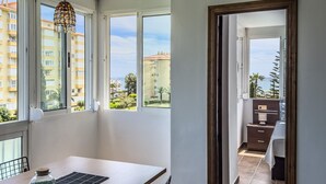 A room with a dining table, a hanging light fixture, and a view of the sea through large windows. - Apartment 'Sol and Sea A121' with Sea View, Wi-Fi and Air Conditioning (El Morche)