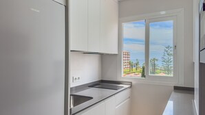 A modern kitchen with white cabinetry, a stainless steel sink, and a window with a view of buildings and trees. - Apartment 'Sol and Sea A121' with Sea View, Wi-Fi and Air Conditioning (El Morche)