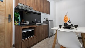 Une cuisine moderne avec des meubles en bois, un four à micro-ondes encastré et un coin repas comprenant une table et des chaises blanches.