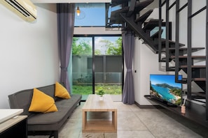 Una sala de estar moderna con un sofá, una mesa de centro, un televisor y una escalera.