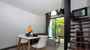 Un coin repas moderne avec une table blanche, deux chaises et un vase de fleurs.