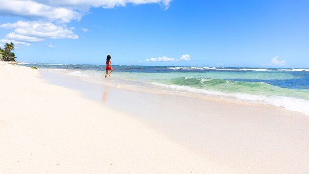 Een strand met heldere lucht en rustige golven.