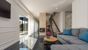 A modern living room with a grey sofa, a round wooden coffee table, and a fireplace. - Villa Cvita Mia Zadarvillas (Privlaka)