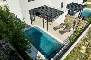 A modern outdoor pool area with lounge chairs and a pergola.