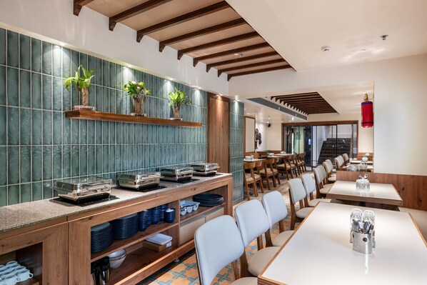 A restaurant with a long counter, multiple seating areas, and a tiled backsplash. - Nine Square Residency (Mumbai)