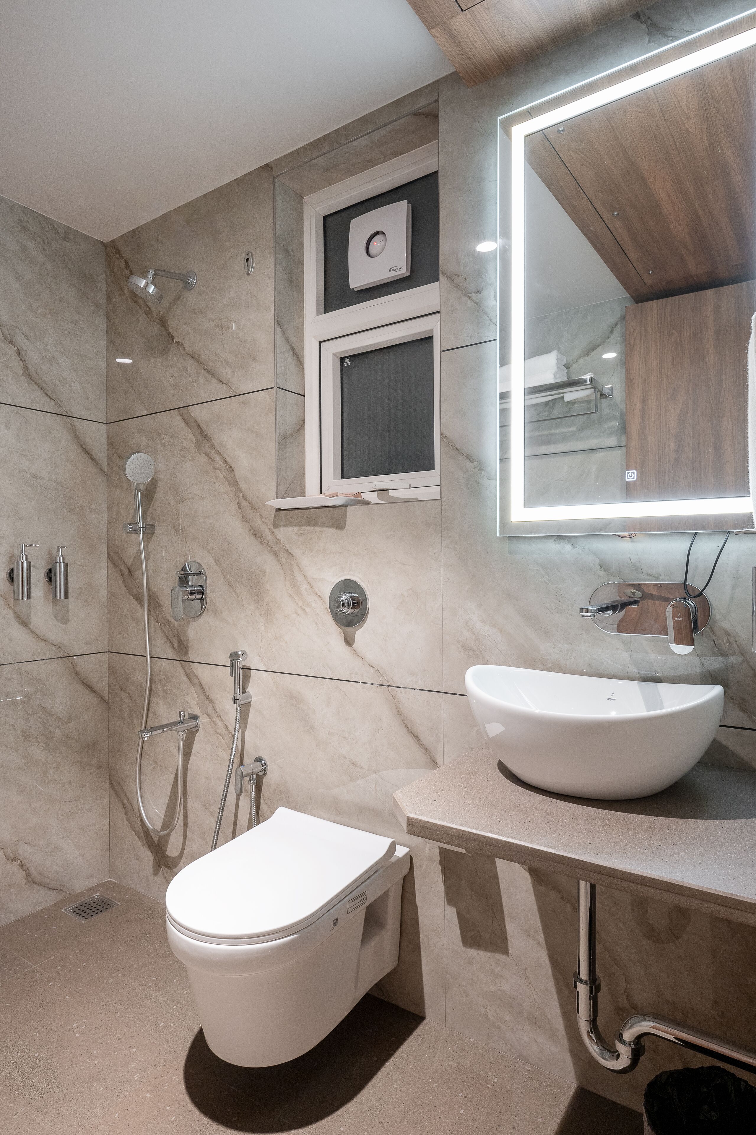 Ein modernes Badezimmer mit Toilette, großem Spiegel und integriertem Waschbecken.