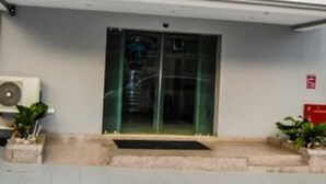 A building entrance with a glass door, a small step leading up, and a fire alarm sign on the wall. - Royal Jatoz Hotel and Suites (Lagos)