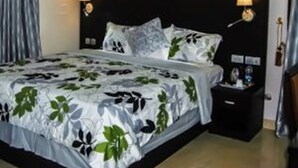 A hotel room with a large bed, two bedside lamps, a nightstand, and a window with curtains. - Royal Jatoz Hotel and Suites (Lagos)