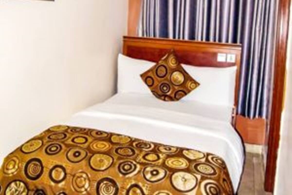 Una habitación de hotel con una cama, un cuadro en la pared y cortinas.