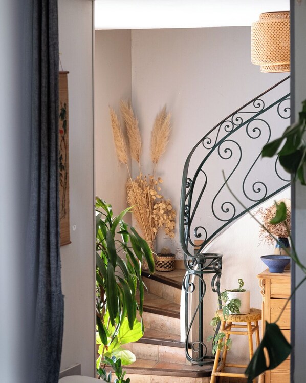 A staircase with a wrought iron railing, a wooden bench, and various potted plants.