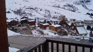 A snow-covered mountain town with wooden buildings and a ski slope in the background.