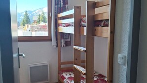 A bunk bed room with a window, a radiator, and a view of mountains.