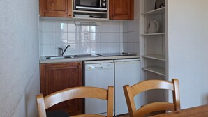 A compact kitchen with wooden cabinets, a microwave, a dishwasher, and a sink.