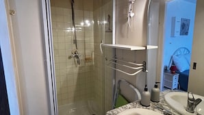 Une salle de bain dotée d’une douche à parois de verre, d’un lavabo avec un plan de travail en marbre et d’un miroir au-dessus du lavabo.