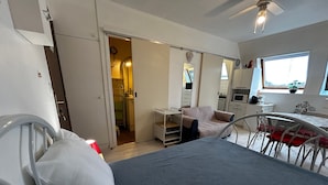 Une chambre avec un lit, un bureau et un coin cuisine.