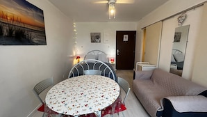 Une pièce chaleureuse avec une table ronde, deux chaises, un canapé, un ventilateur de plafond et une porte sur laquelle est apposée une pancarte indiquant « accès interdit ».