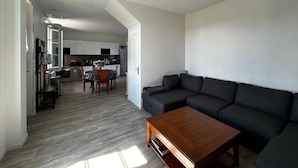 A modern living room with a dark sofa, a wooden coffee table, and a dining area with a table and chairs. - Renovated House with Garden and WIFI in La Roche-Posay (La Roche-Posay)