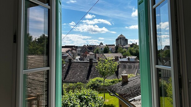 A view through a window with a clear sky, a water tower, and traditional buildings. - Renovated House with Garden and WIFI in La Roche-Posay (La Roche-Posay)