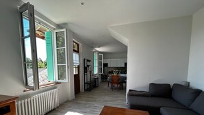 A modern living room with a grey sofa, a wooden coffee table, and a view of a kitchen and dining area through an open door. - Renovated House with Garden and WIFI in La Roche-Posay (La Roche-Posay)