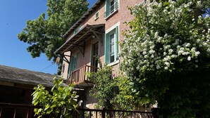 A two-story building with a balcony, green shutters, and white flowering plants. - Renovated House with Garden and WIFI in La Roche-Posay (La Roche-Posay)