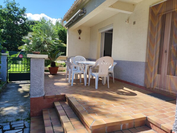 Un patio con mesa y sillas, una planta en maceta y una reja.