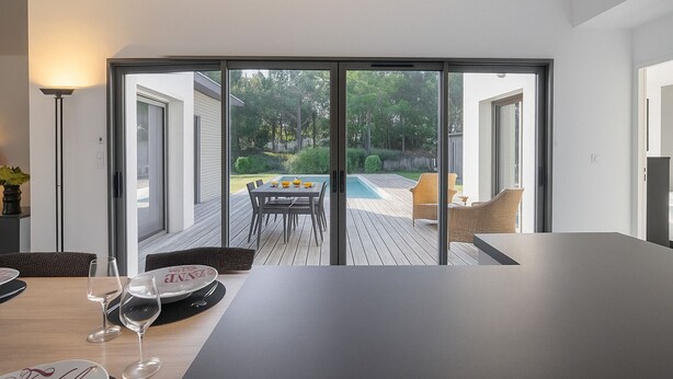 Ein moderner Essbereich mit großem Tisch, einem Pool und Blick auf den Garten.
