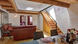 Una habitación acogedora con techo de madera, un sofá, una mesa de comedor con comida y una escalera.