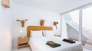 A modern bedroom with a large bed, two nightstands, a woven headboard, and decorative wall art.