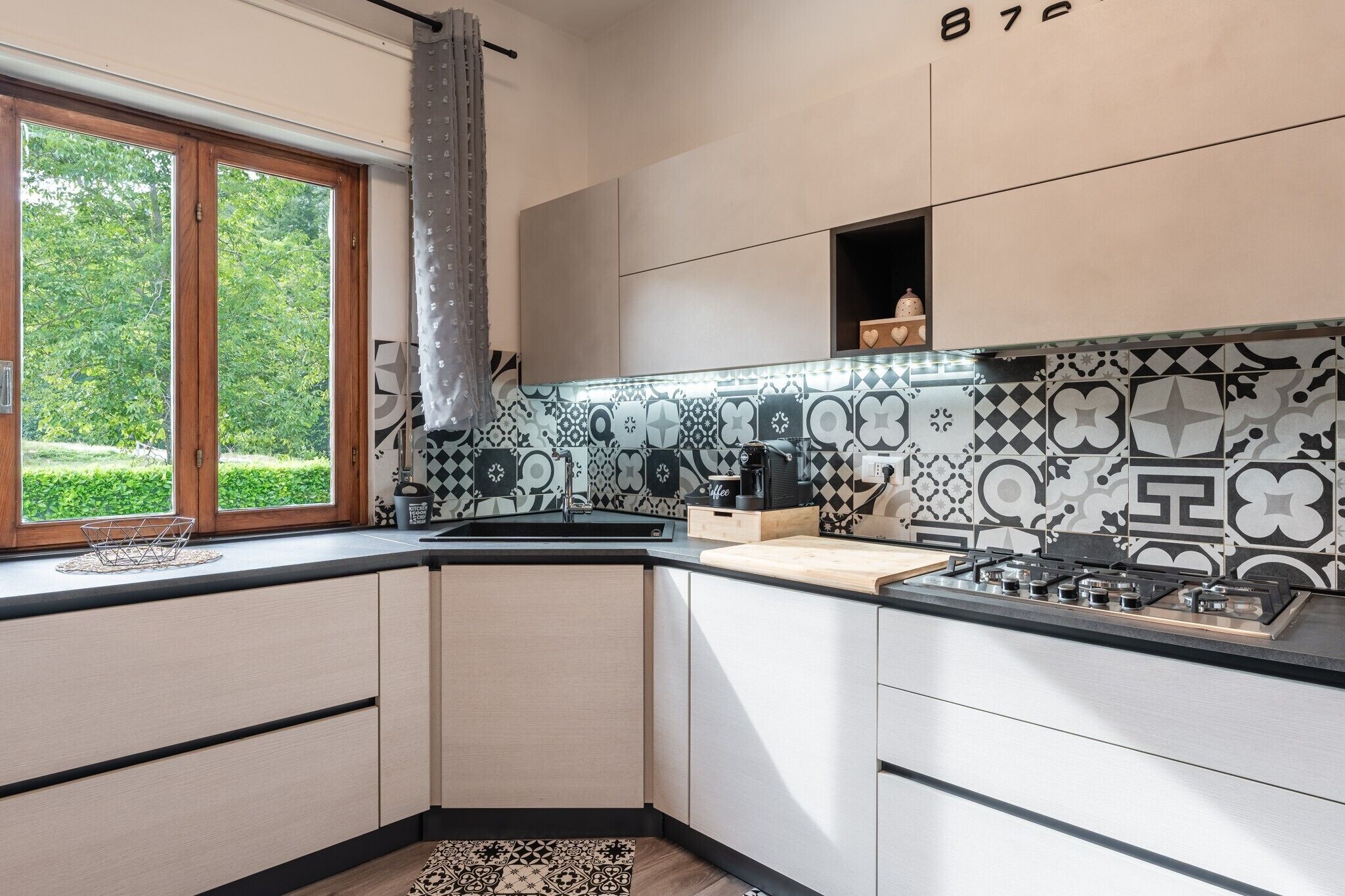 Une cuisine moderne dotée d’une grande fenêtre, d’un crédence décorée et d’une cuisinière intégrée.
