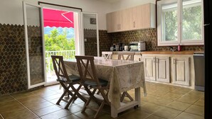 A kitchen with a dining area, a view of greenery, and a red umbrella. - Apartment in Furiani near Bastia, 3 bedrooms, pool (Furiani)