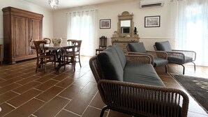 A spacious living room with a dining area, wicker furniture, a large cabinet, and a chandelier. - Apartment in Furiani near Bastia, 3 bedrooms, pool (Furiani)