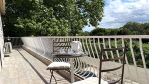 An outdoor seating area with a table and chairs, a white railing, and a view of trees and sky. - Apartment in Furiani near Bastia, 3 bedrooms, pool (Furiani)