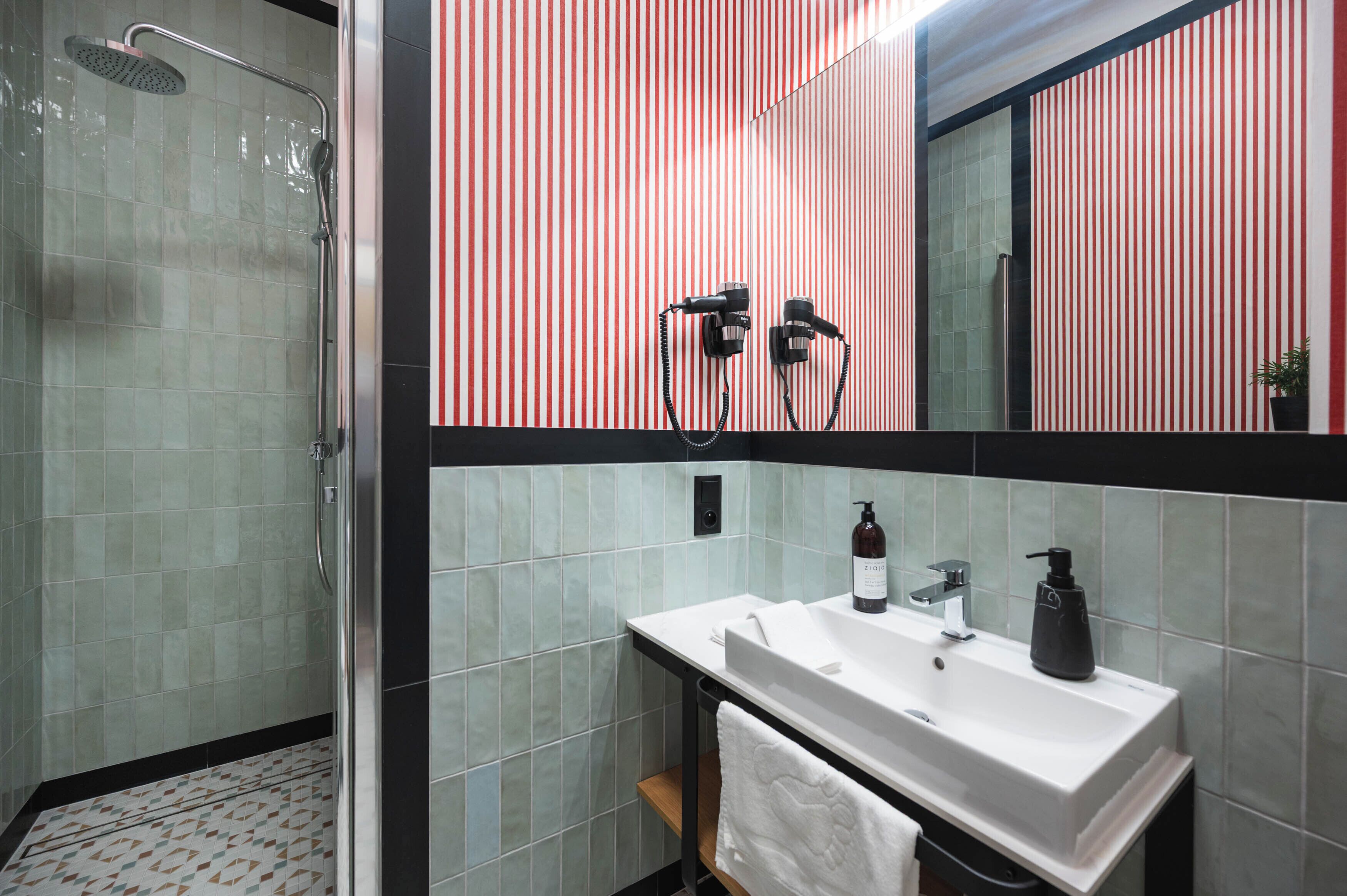 Een badkamer met een douche, wastafel en spiegel.