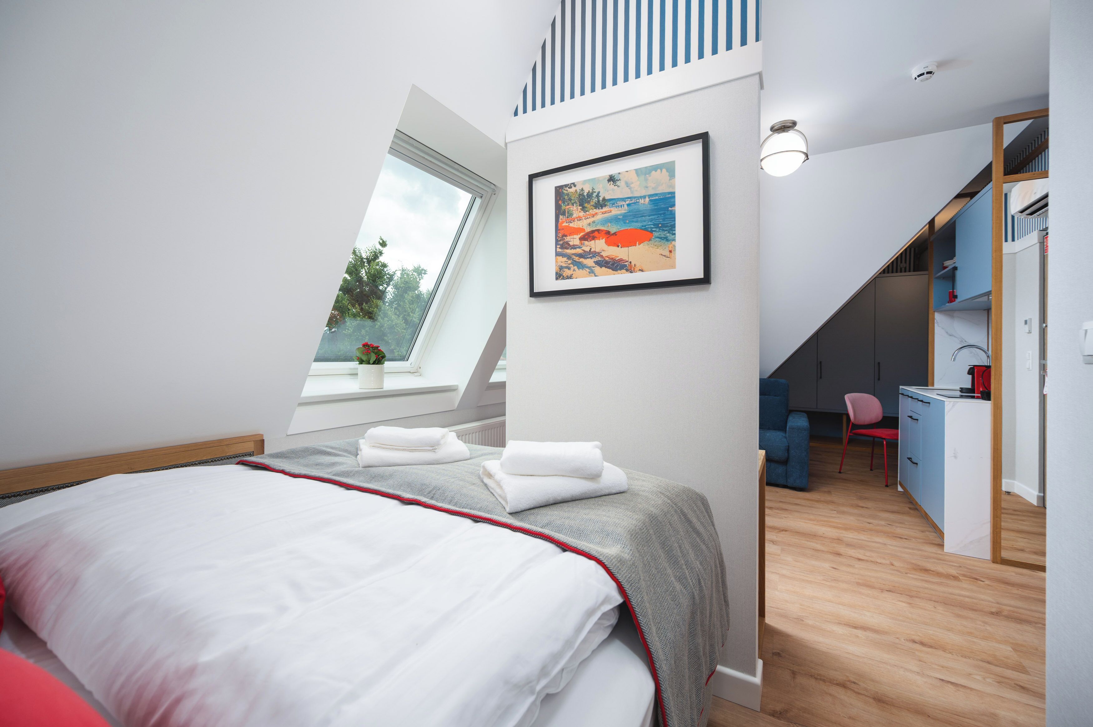 A bedroom with a bed, a desk, and a chair. There is a window with a view of trees.