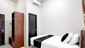 A hotel room with a bed, a wardrobe, a door, and an air conditioning unit. - Hotel O Balikpapan near Siloam Hospital formerly Syafla Guest House (Balikpapan)