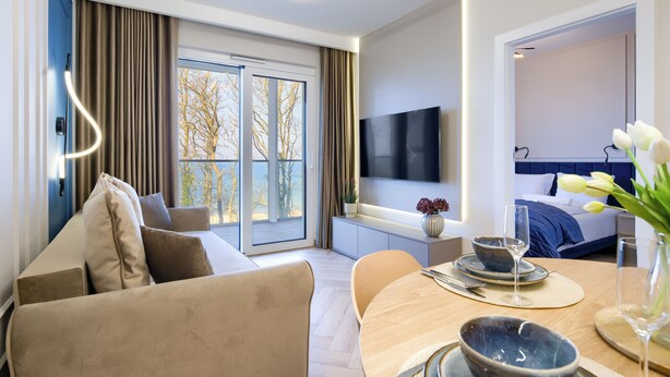 Una camera d'albergo moderna con divano, tavolo da pranzo e televisione.
