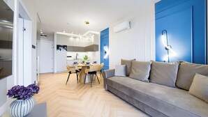 Un soggiorno moderno con un divano, un tavolo da pranzo con sedie e una cucina sullo sfondo.