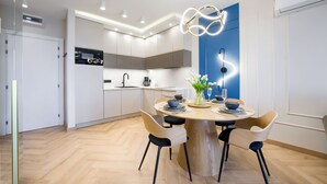 Una cucina moderna con forno integrato, un'area pranzo con tavolo rotondo e sedie, e una parete decorata in blu.