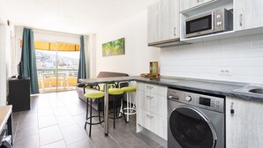 A modern kitchen with a built-in microwave, a washing machine, and a dining area with bar stools. - Stunning sea view apt in Los Cristianos (Los Cristianos)