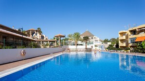 A swimming pool with a lifebuoy, surrounded by buildings with balconies and palm trees. - Stunning sea view apt in Los Cristianos (Los Cristianos)