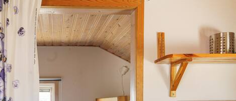 A compact room with a bunk bed, a wooden dresser, a small window, and a blue storage bin.