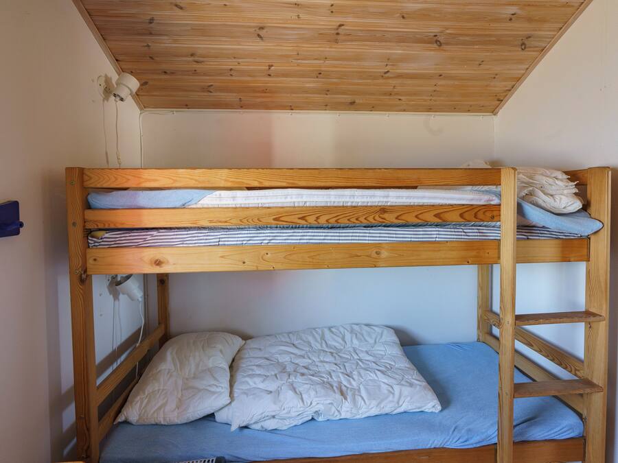 Un lit superposé avec une structure en bois, un matelas bleu et une couette blanche.