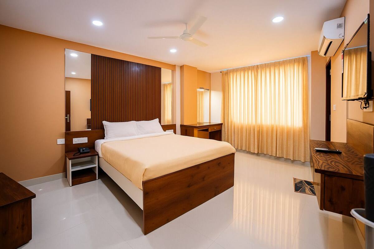 Un dormitorio moderno con una cama de madera, una mesita de noche, un espejo, un ventilador de techo y una ventana con cortinas.