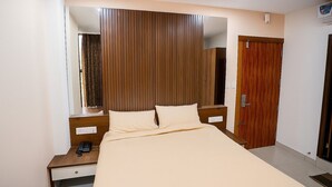 Ein Schlafzimmer mit Bett, Nachttisch, Spiegel, Holzschrank und einer Tür.