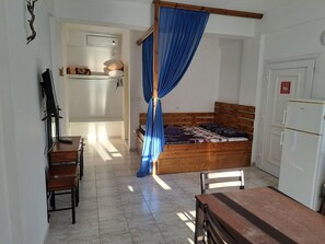 A small room with a bed, a desk, a chair, a wardrobe, and a curtain.