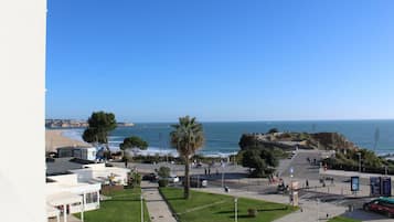 Blick auf die Küste mit einer gepflasterten Promenade, Palmen und einem Strand im Hintergrund.