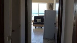 A corridor leading to a living area with a sofa and a refrigerator. - Praia Rocha Balcony First Line Beach View Studio (Portimão)