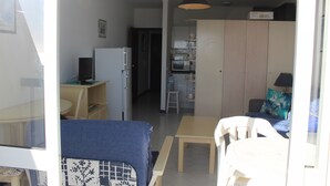 A compact living space with a kitchenette, a dining area, and a seating area. - Praia Rocha Balcony First Line Beach View Studio (Portimão)